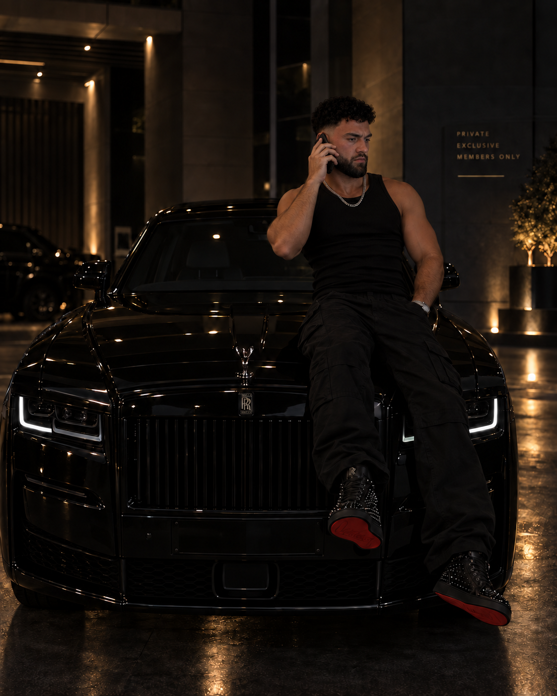 Founder wearing a black vest while sitting on a black car at night